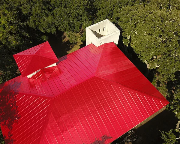Aerial view of a red metal roof on a home among trees