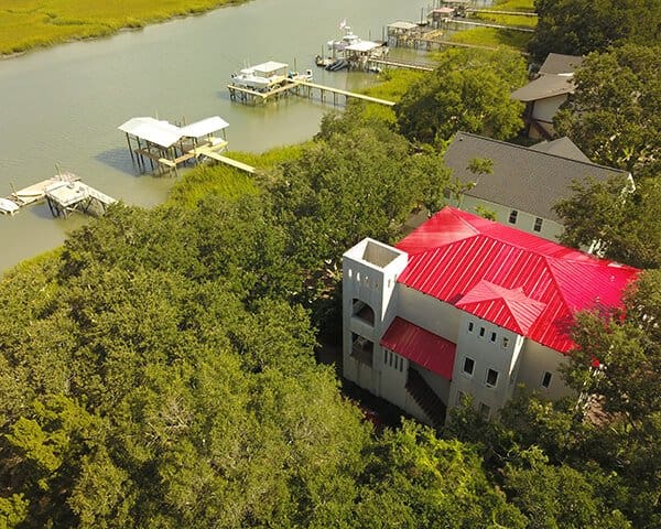 Aerial view of a two-story home with a finished red metal roof