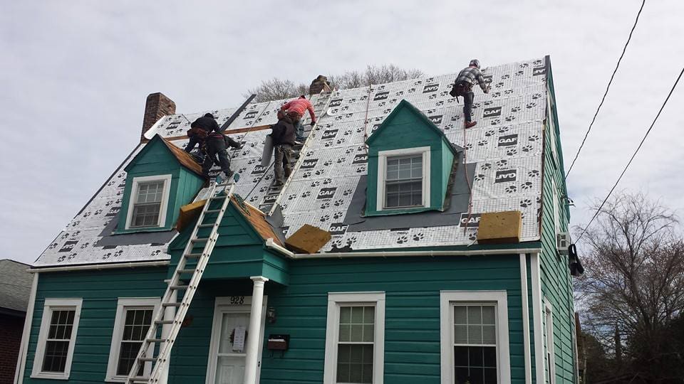 Powell Roofing crew working on the steep roof of a two-story home